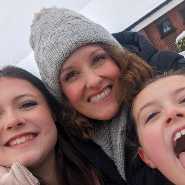 Profile picture of Emma smiling and small portion of two childrens faces.
